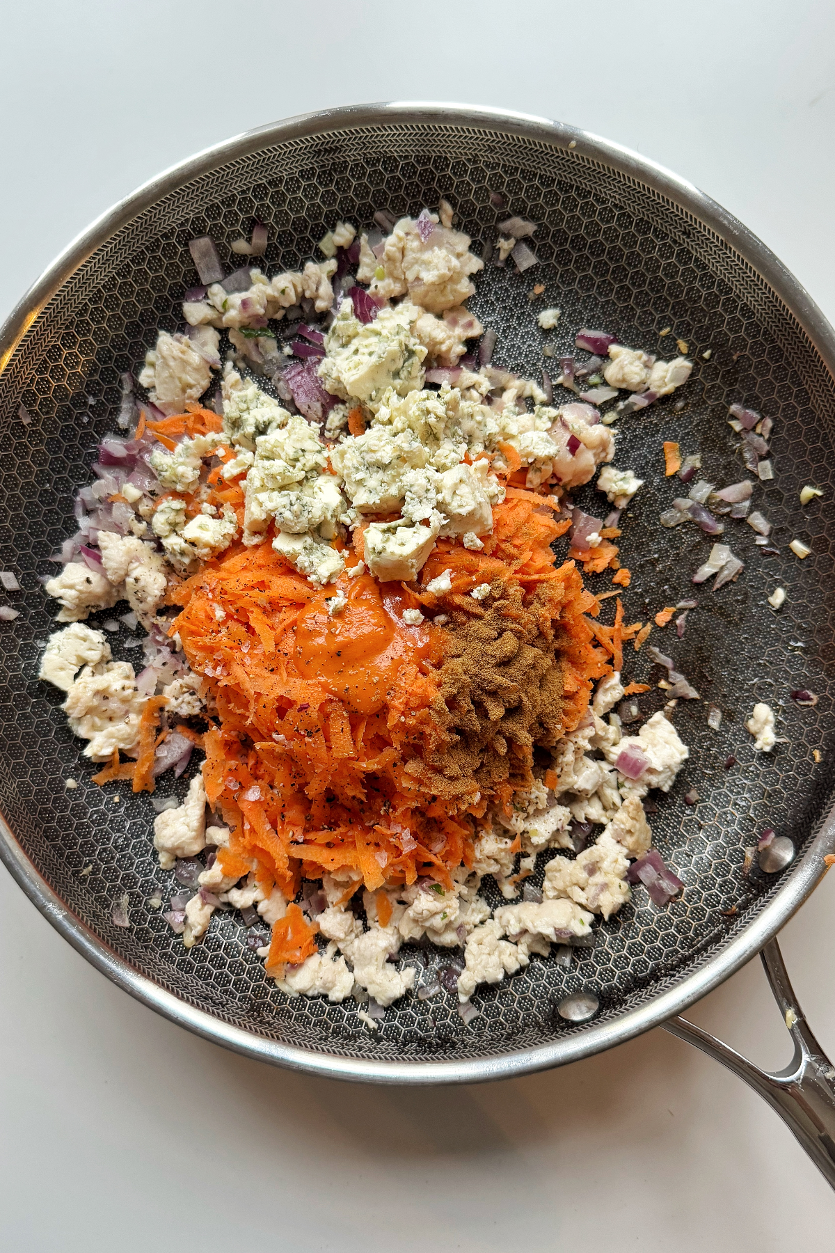 Adding blue cheese and carrots to the ground chicken stuffed peppers mix.