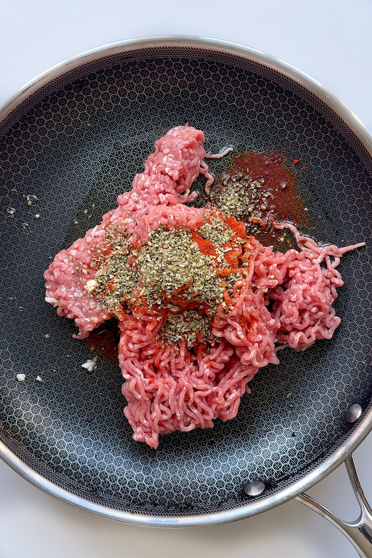Frying ground pork with spices and herbs in a pan.