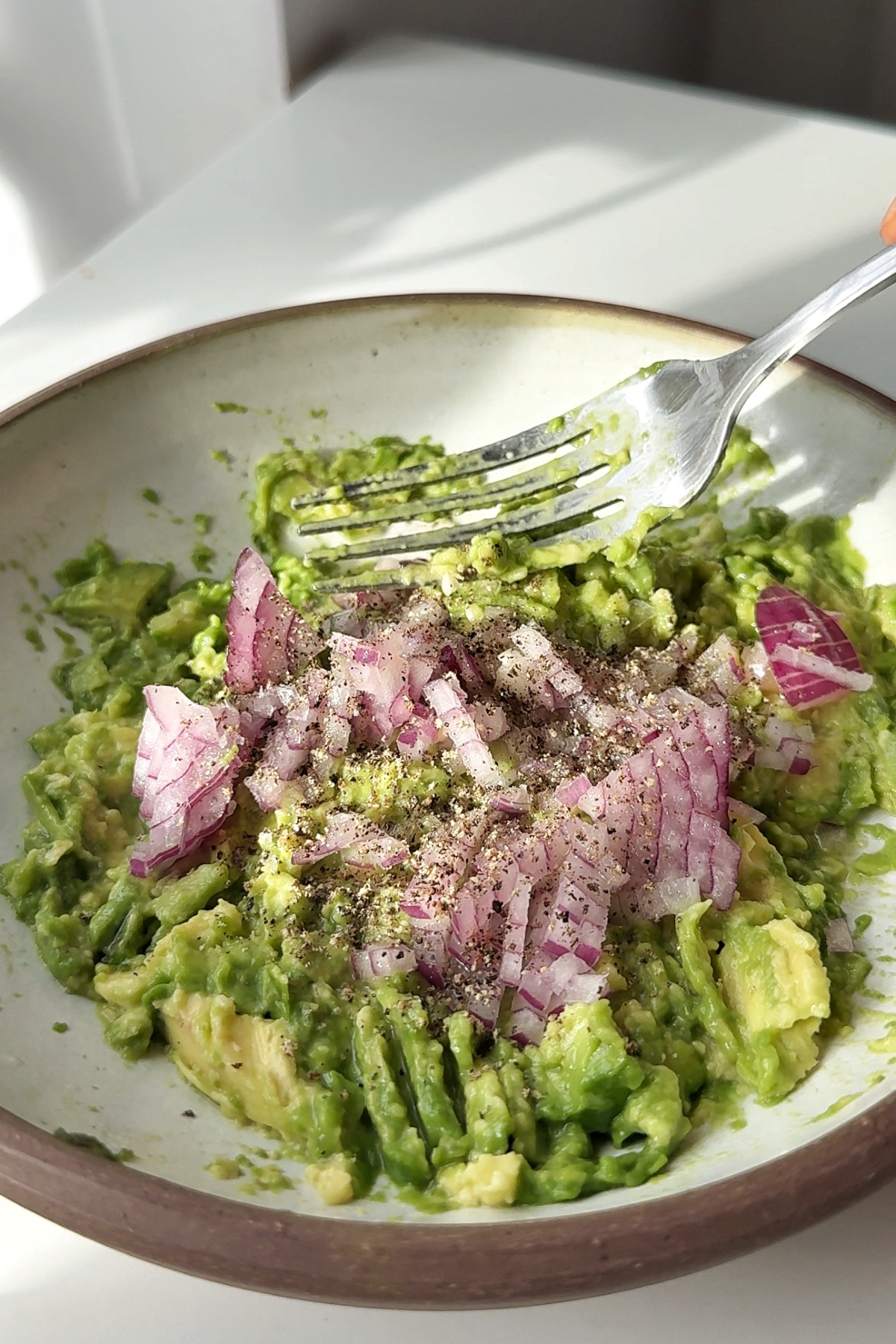 Making smashed avocado with red onion.
