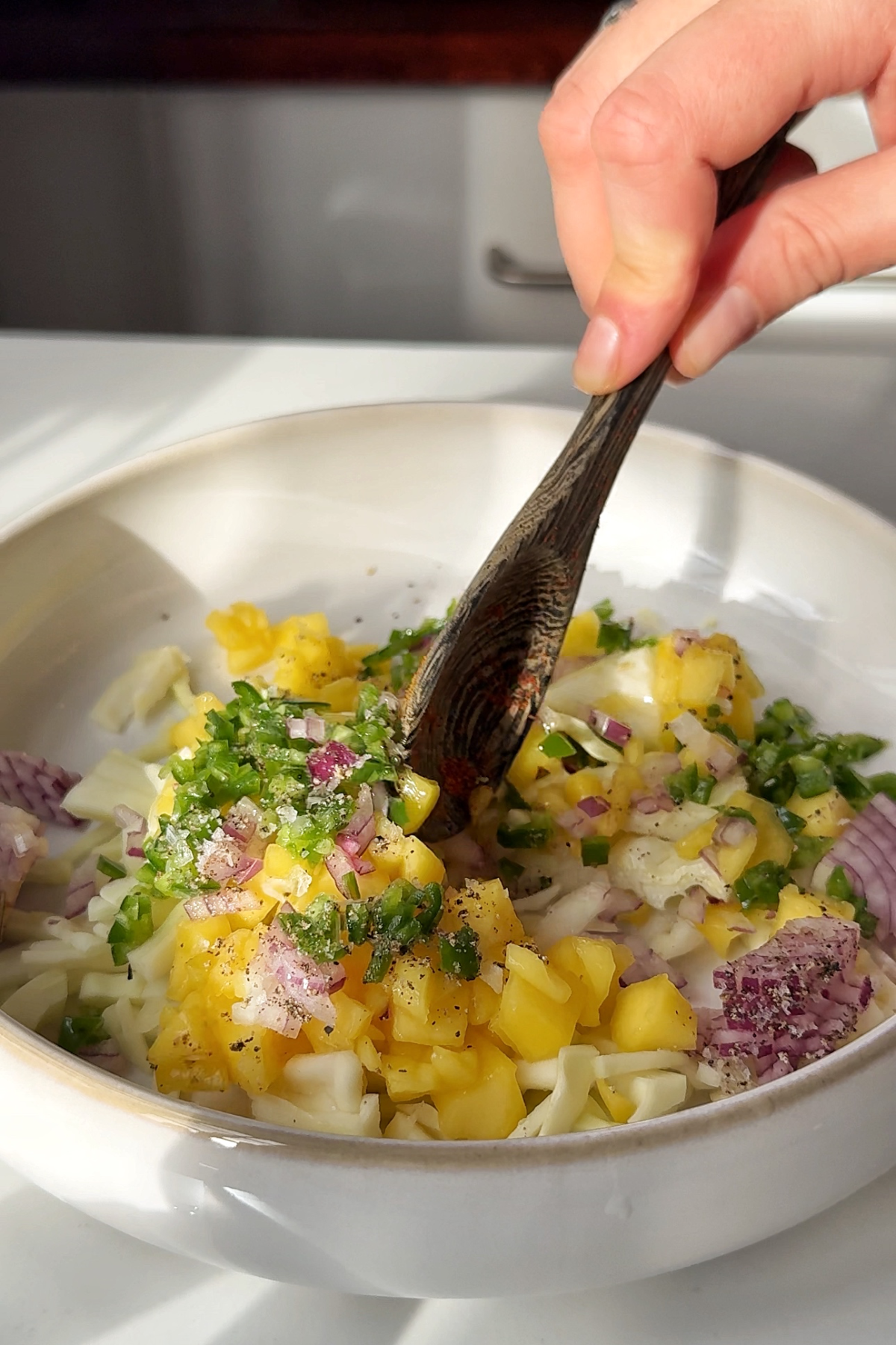 Making mango salsa in a white bowl.