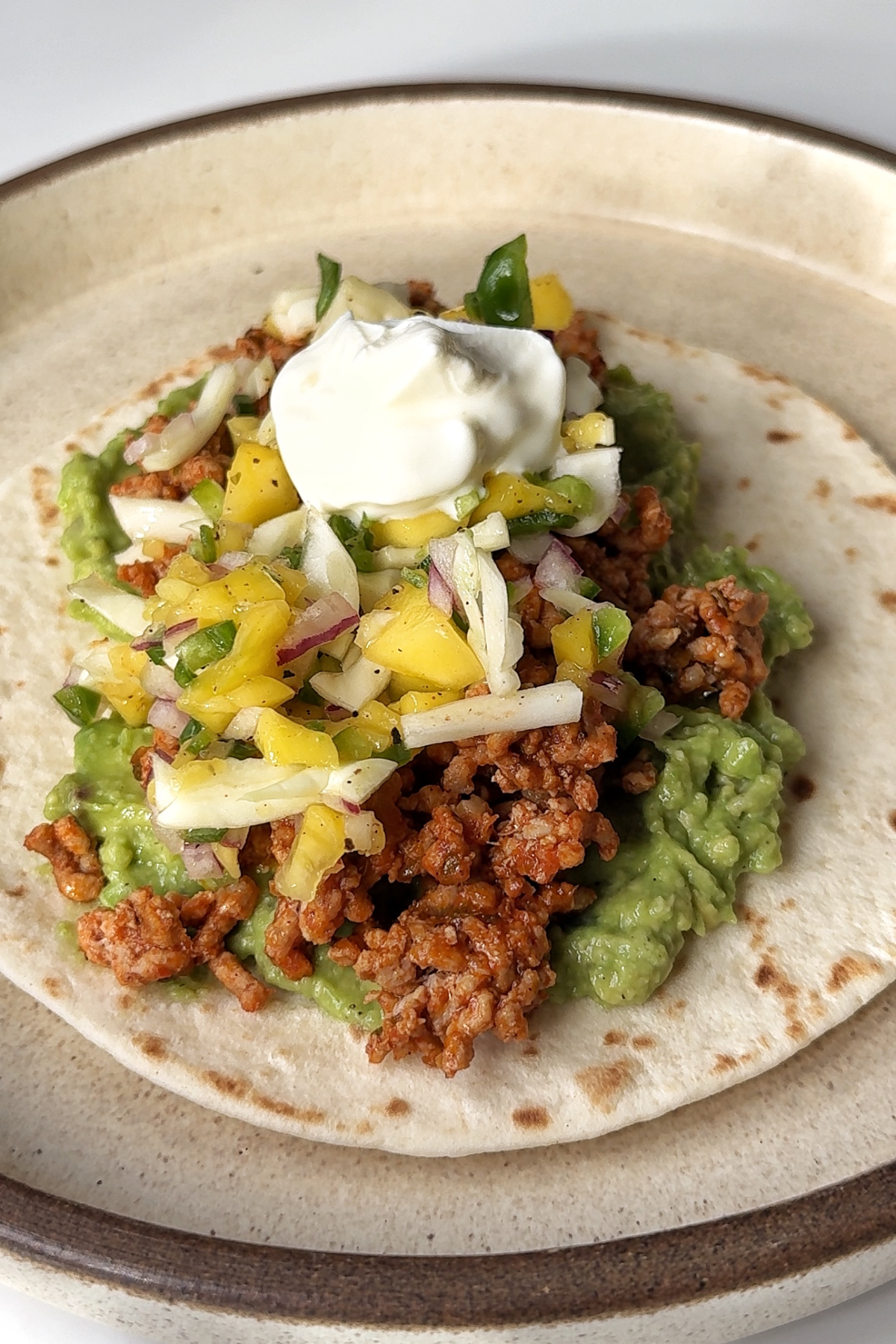 Assembling the ground pork tacos on a plate.