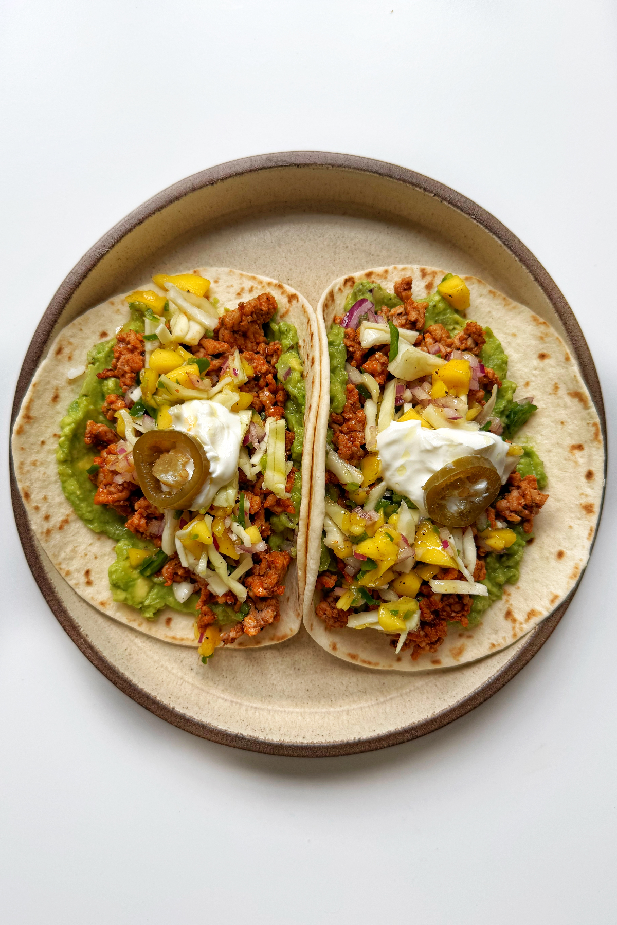ground pork tacos topped with chili mango salsa, sour cream, and jalapeño.