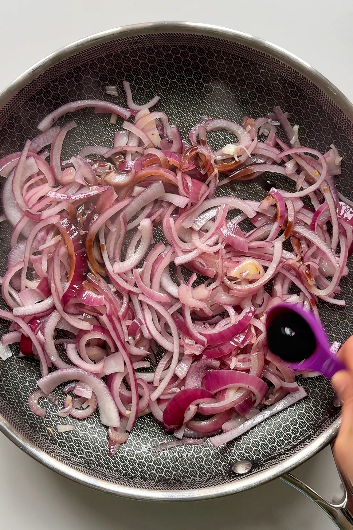 Frying the red onions in a black pan.