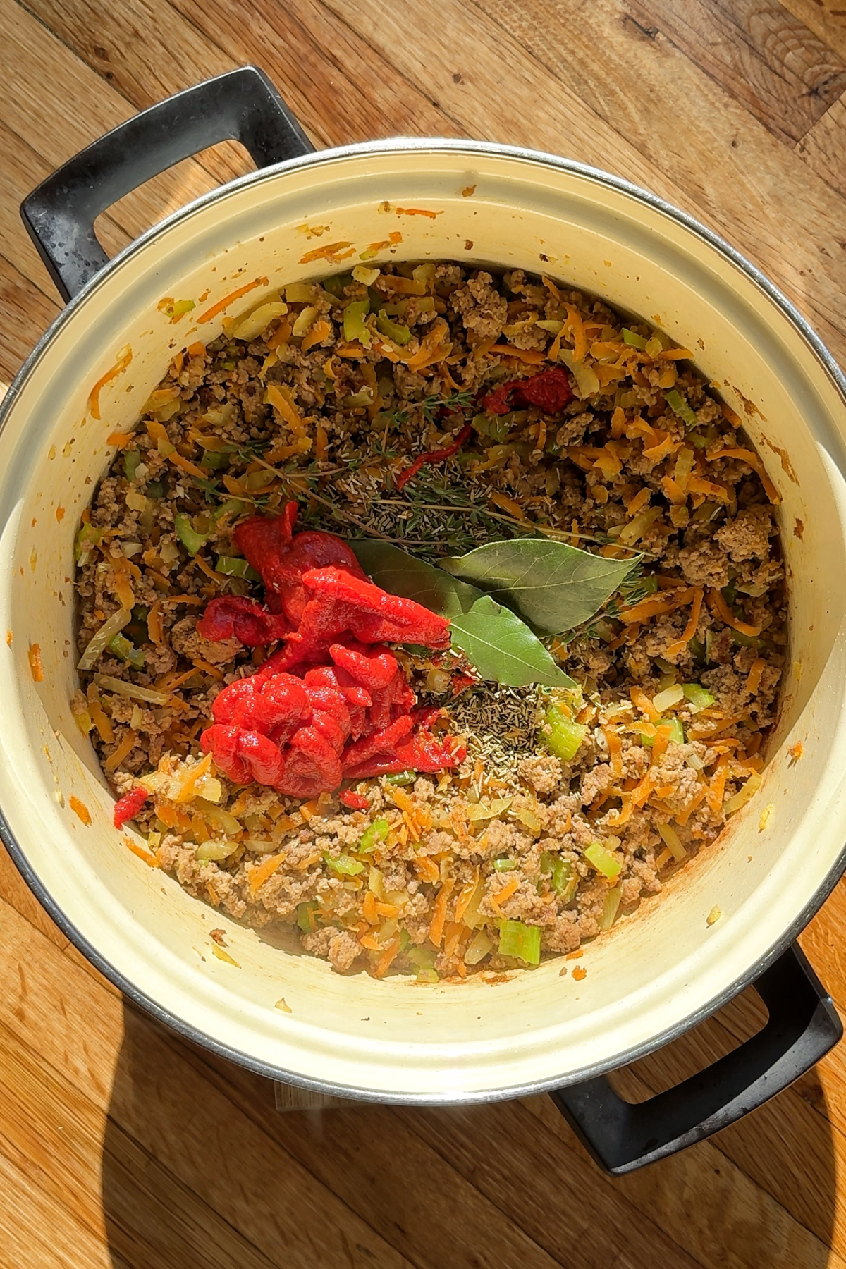 Adding the herbs and tomato paste to the shepherds pie filling.