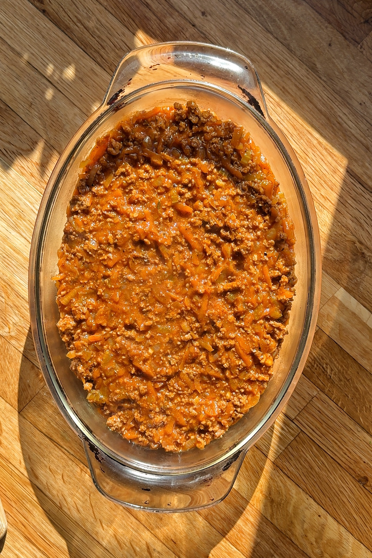 Layering the lamb mince filling on the base of the dish.