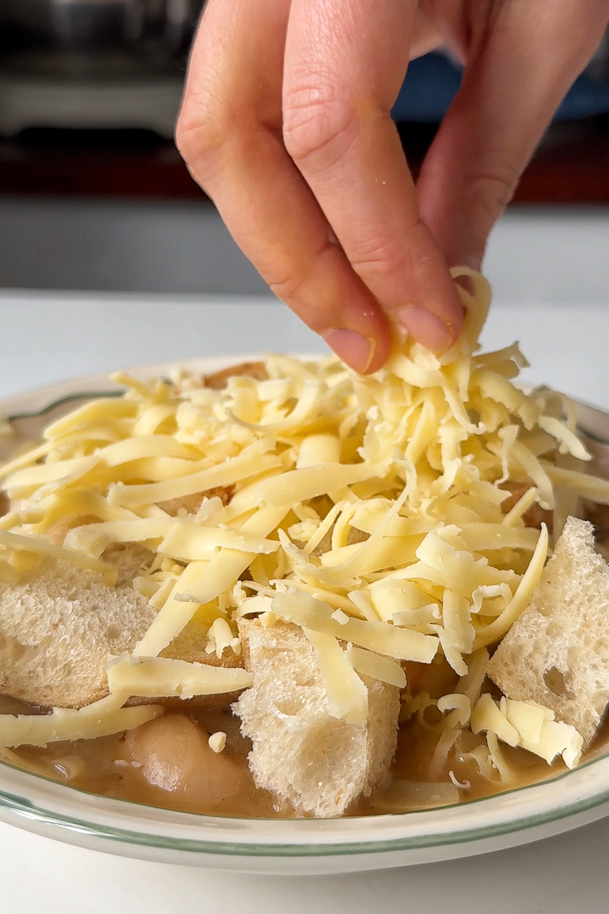 Topping the butter bean soup with baguette and cheese.