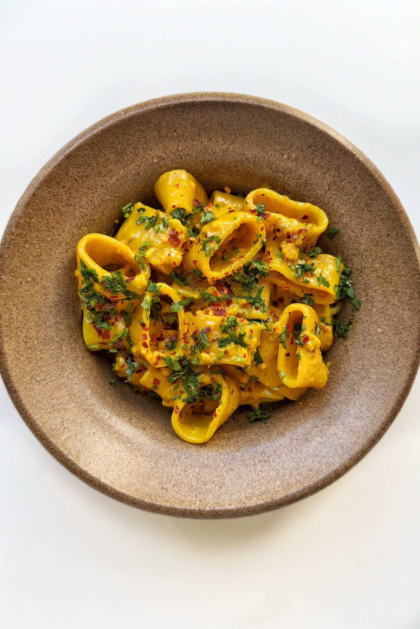 Served up curry pasta in brown bowl.