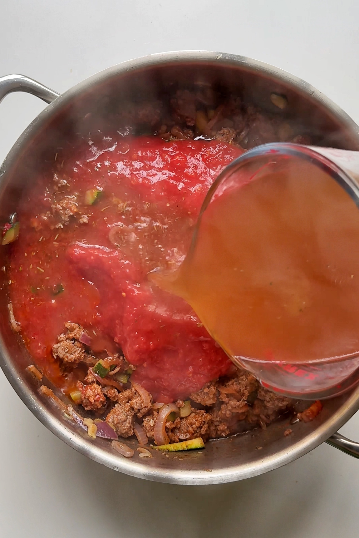 Adding tomato to the one pot lasagna.