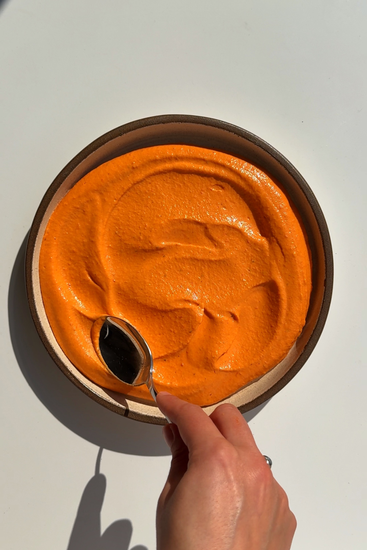 Plating up the smooth and creamy roasted red bell pepper hummus.