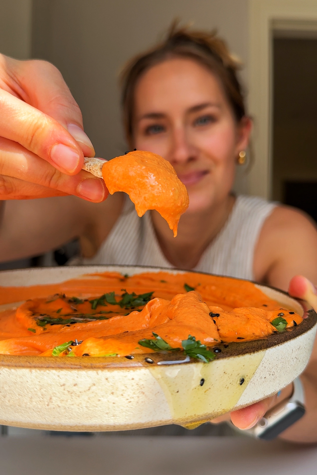 Emily showing roasted red pepper hummus on pitta to the camera.
