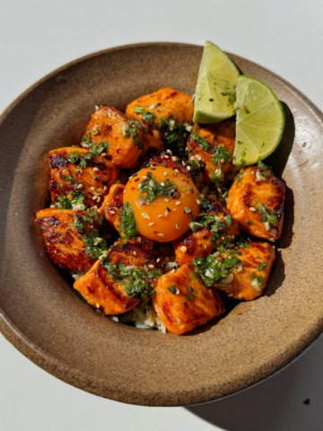 Avocado rice bowl with salmon bites and lime wedges.