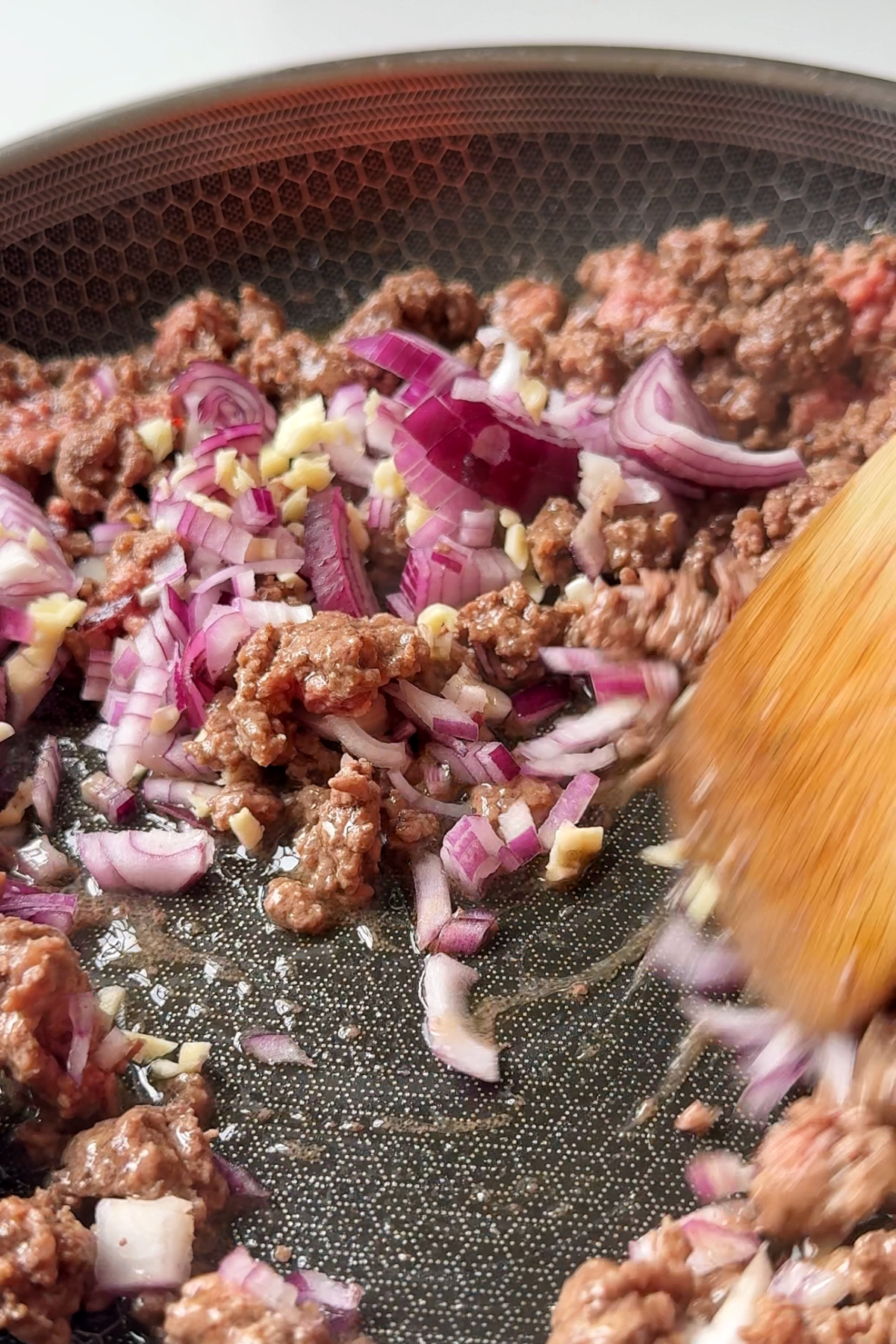 Frying off the beef, onion, and garlic in a pan.