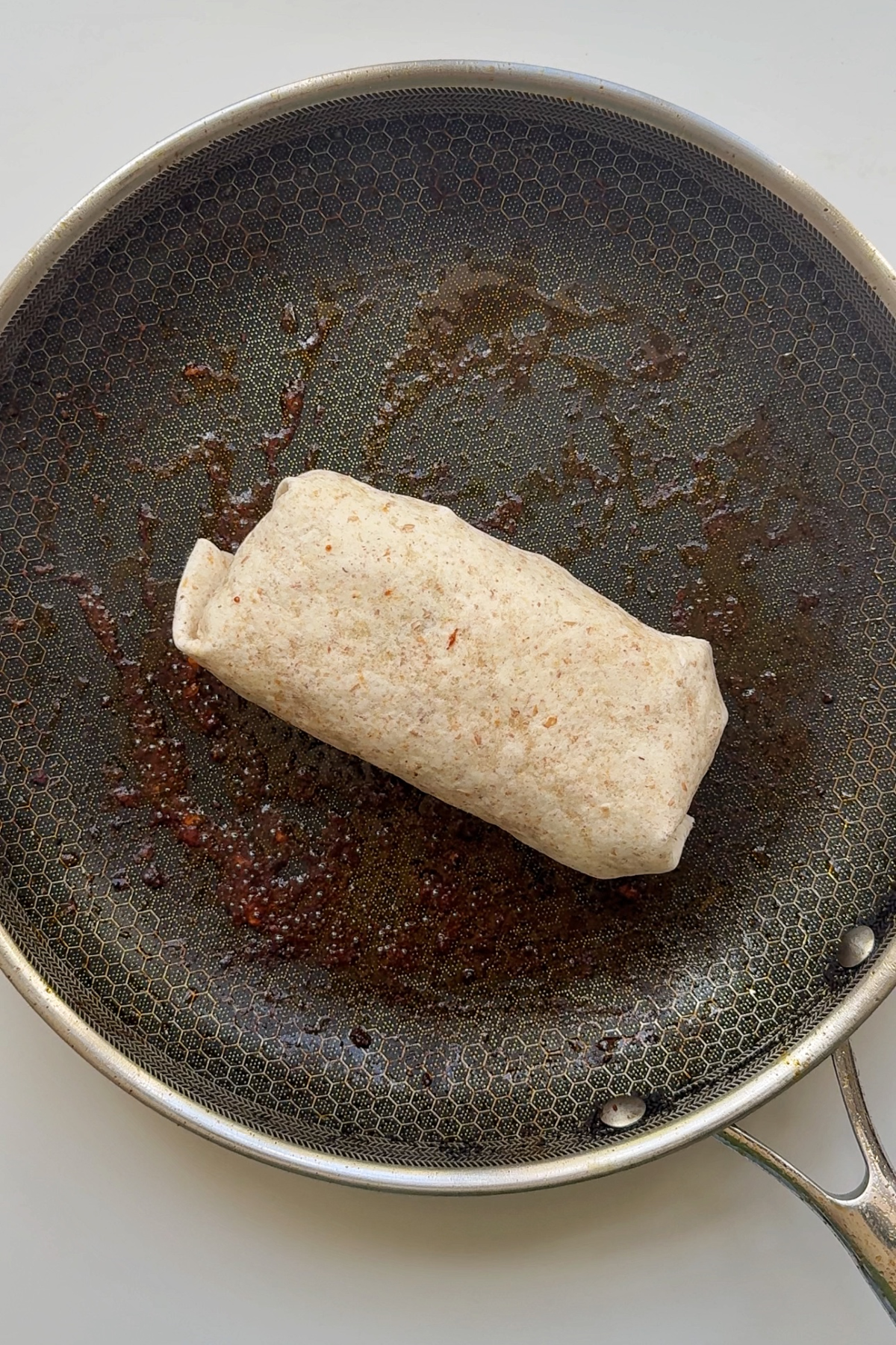 Frying the buffalo chicken wrap in a black frying pan.