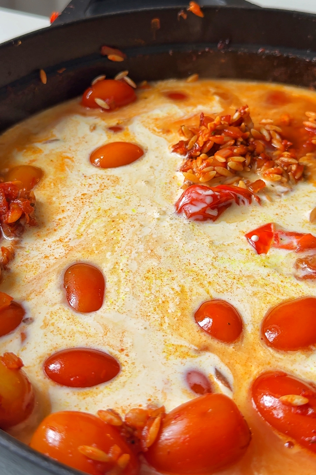 Adding cream and stock into a one pan orzo dish.