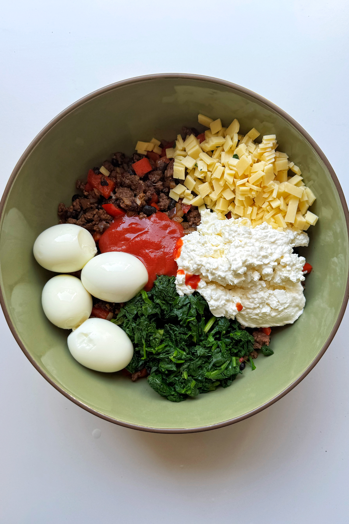 Adding all of the high protein burrito ingredients in a bowl.