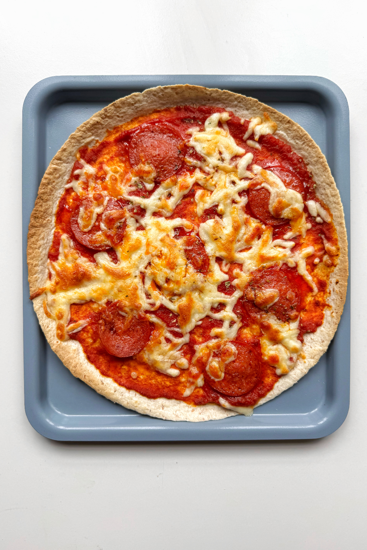Pizza wrap cooked on a blue tray.
