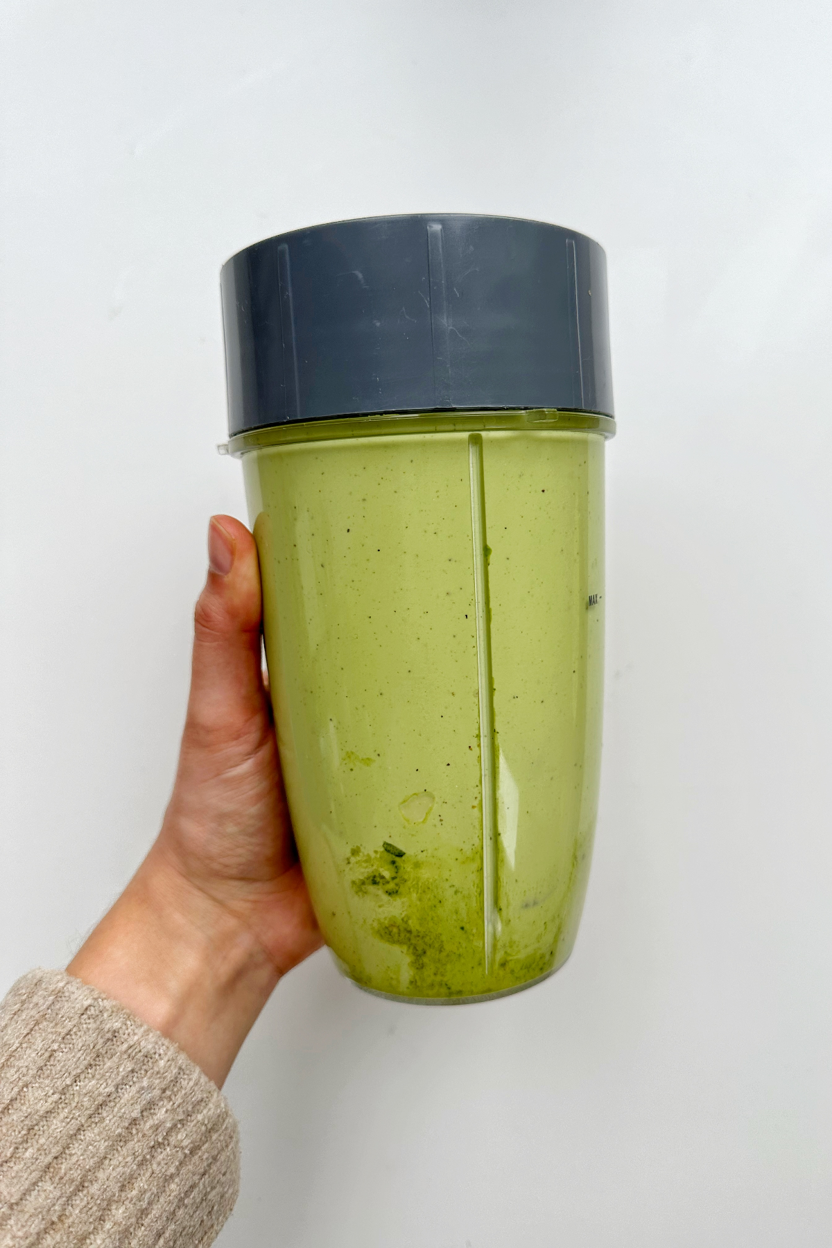 A blender with blended green avocado guacamole in it.