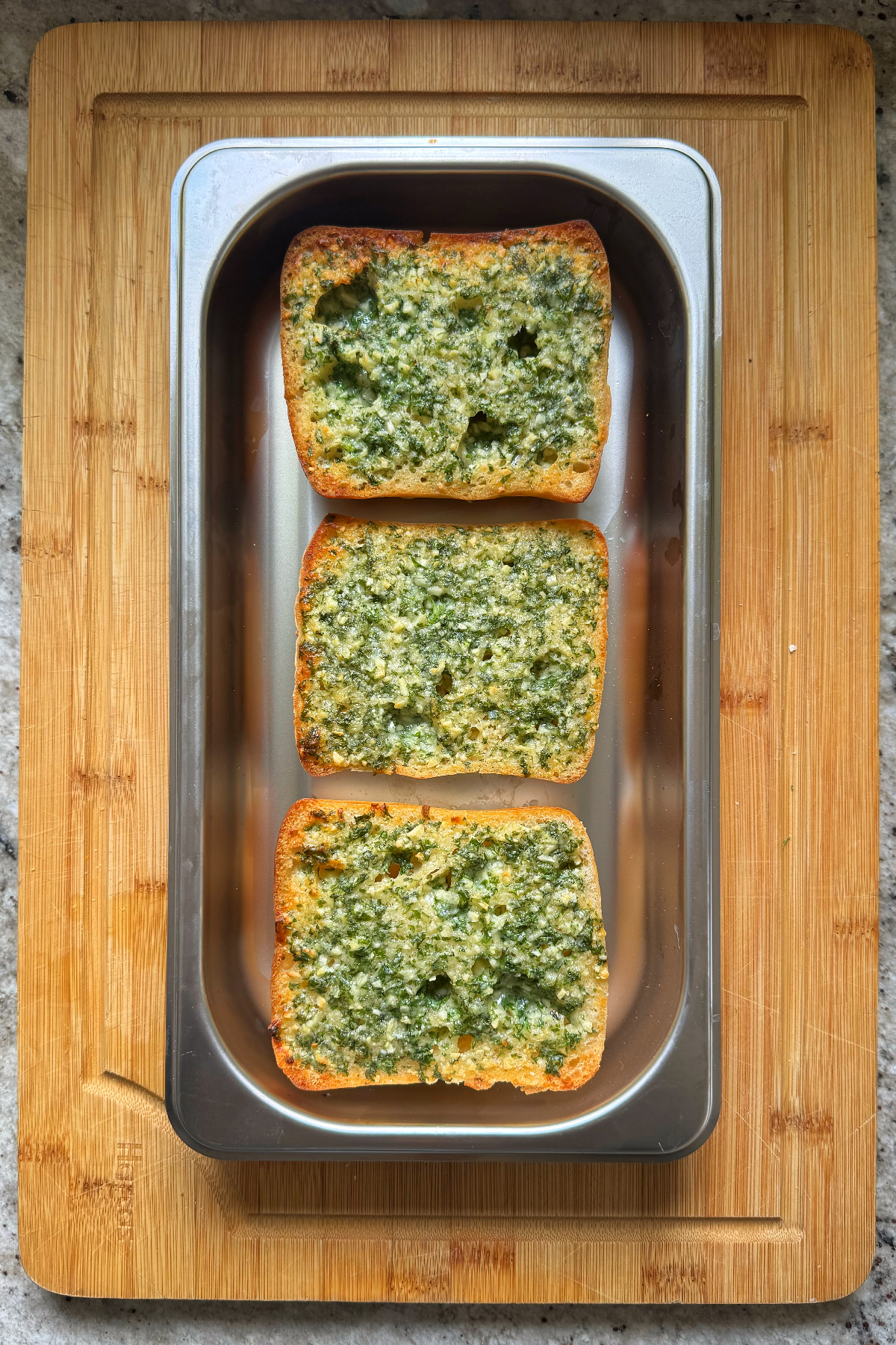 Oven-baked ciabatta garlic bread in tray.