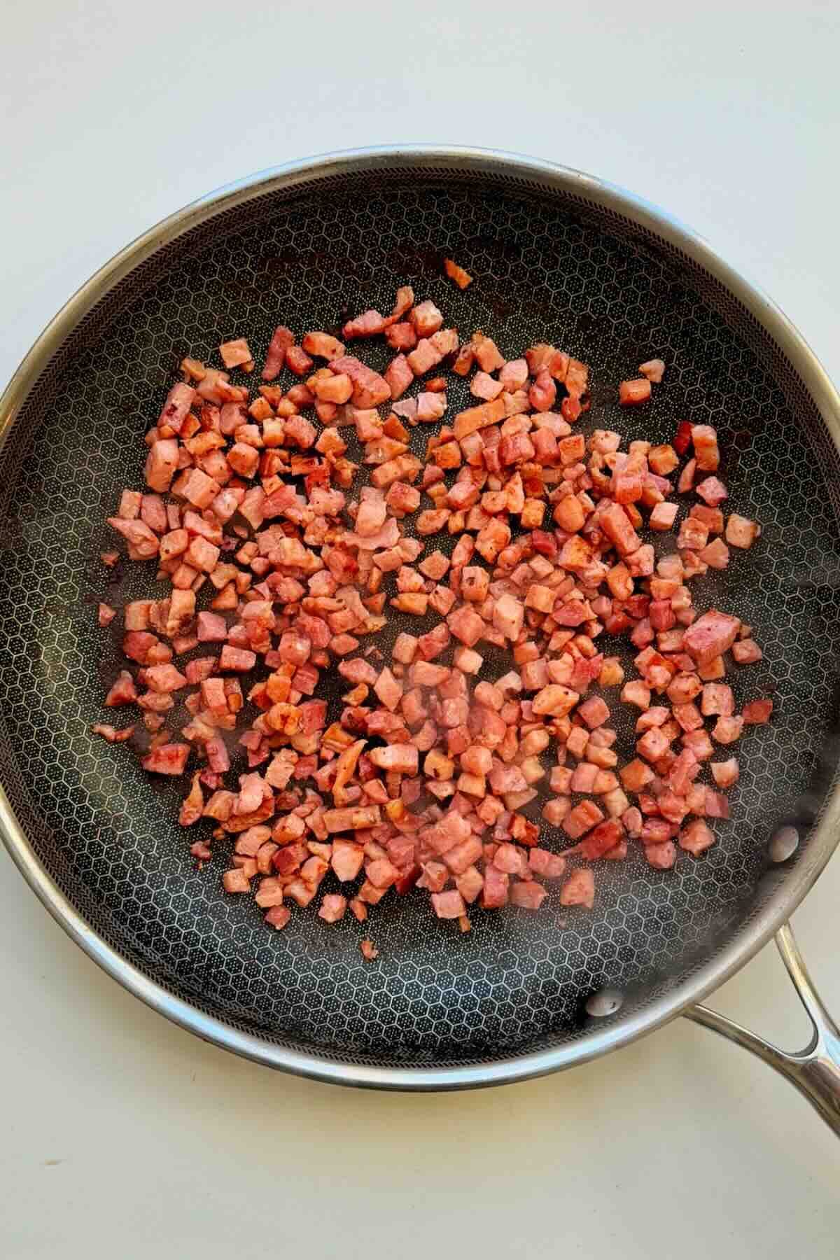 Crunchy bacon bits in a frying pan.