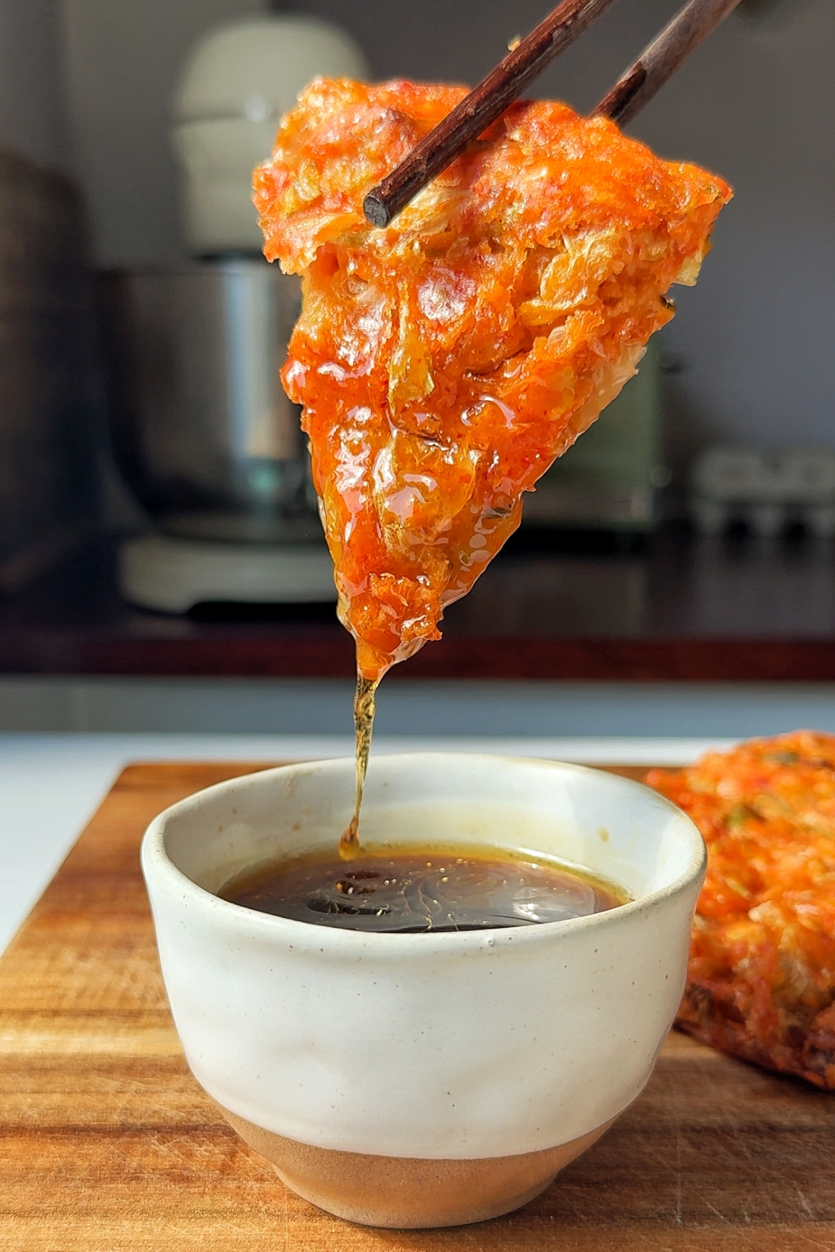 Kimchijeon slice dipped in sauce.