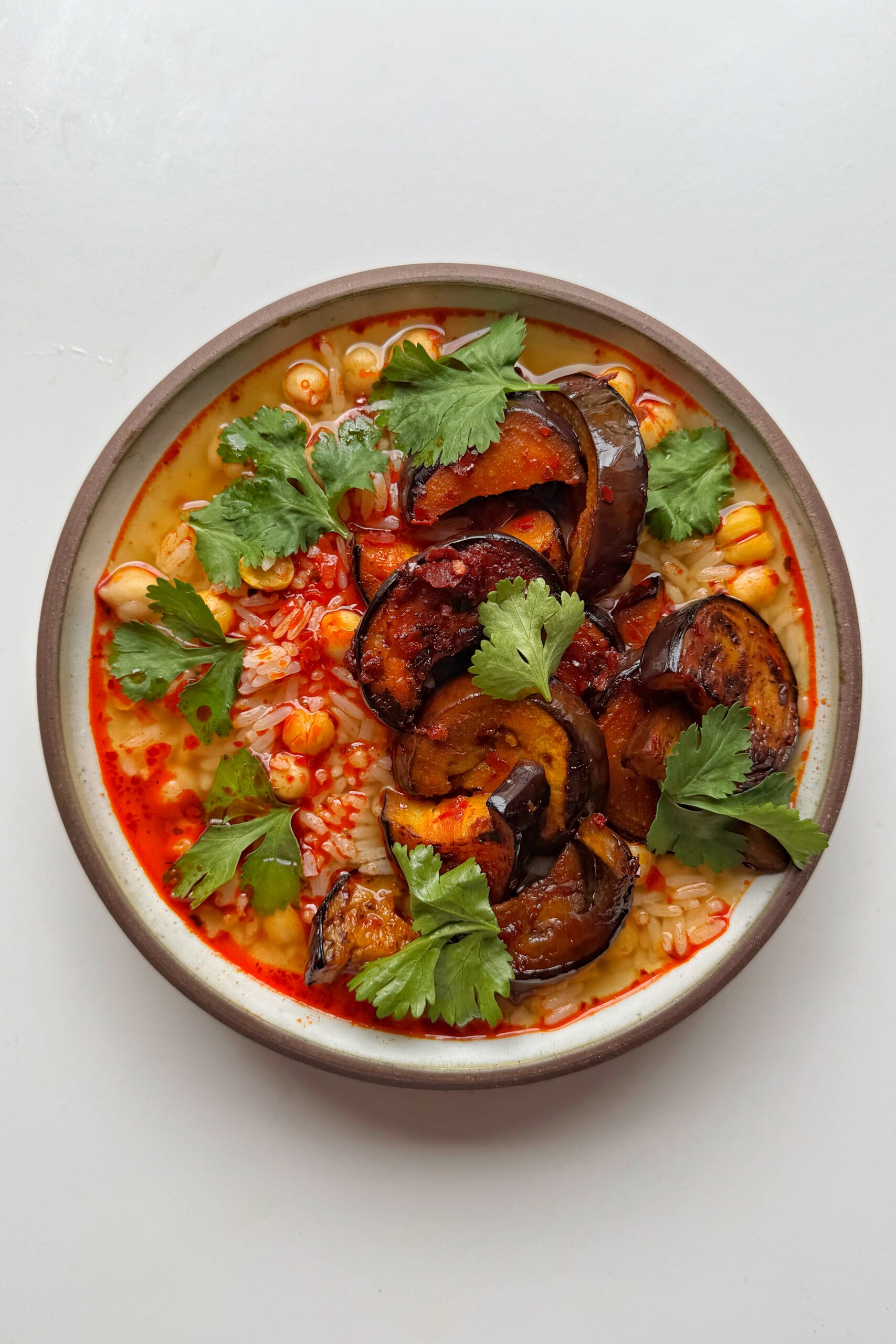 harissa rice with aubergine in a bowl on white surface.