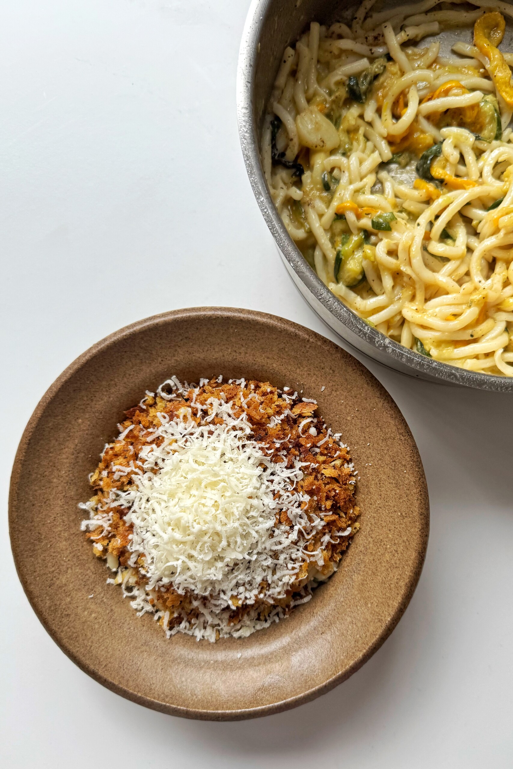 Bowl of courgette noodles with pan next to it.
