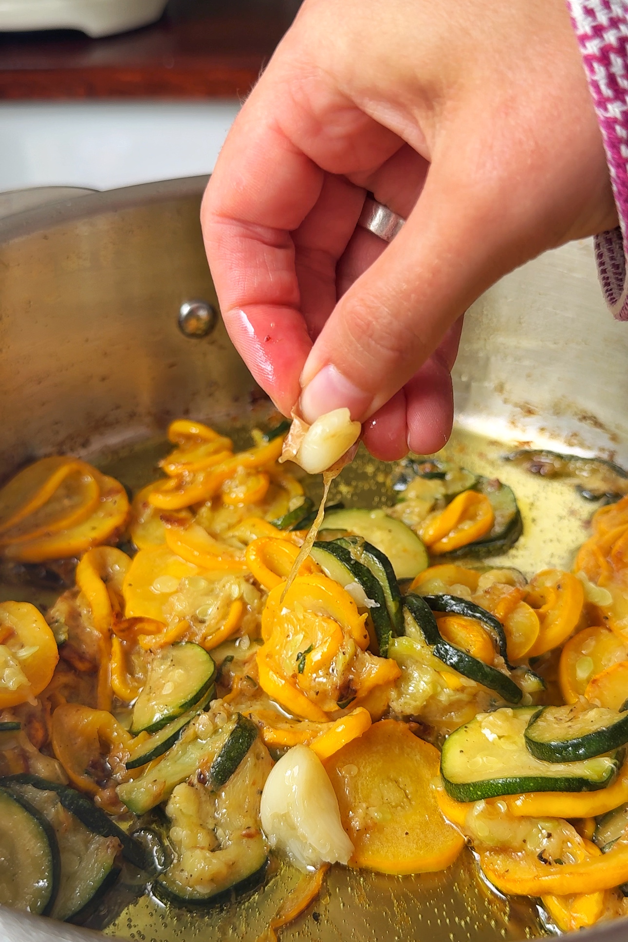 Squeezing garlic into pasta dish.