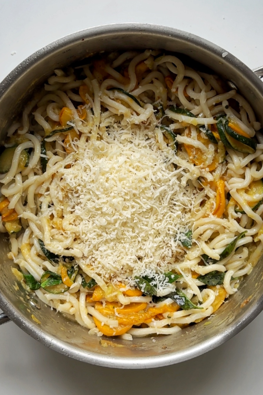 Adding parmesan to the courgette pasta dish.