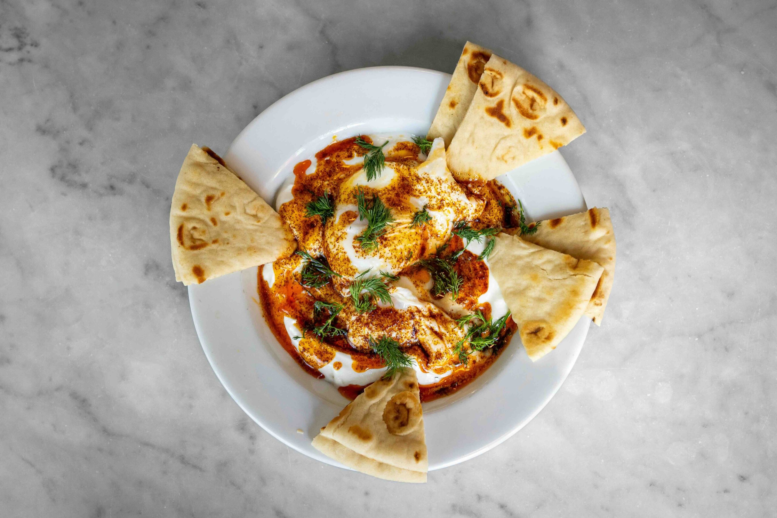 A bowl of labneh and pita breads.
