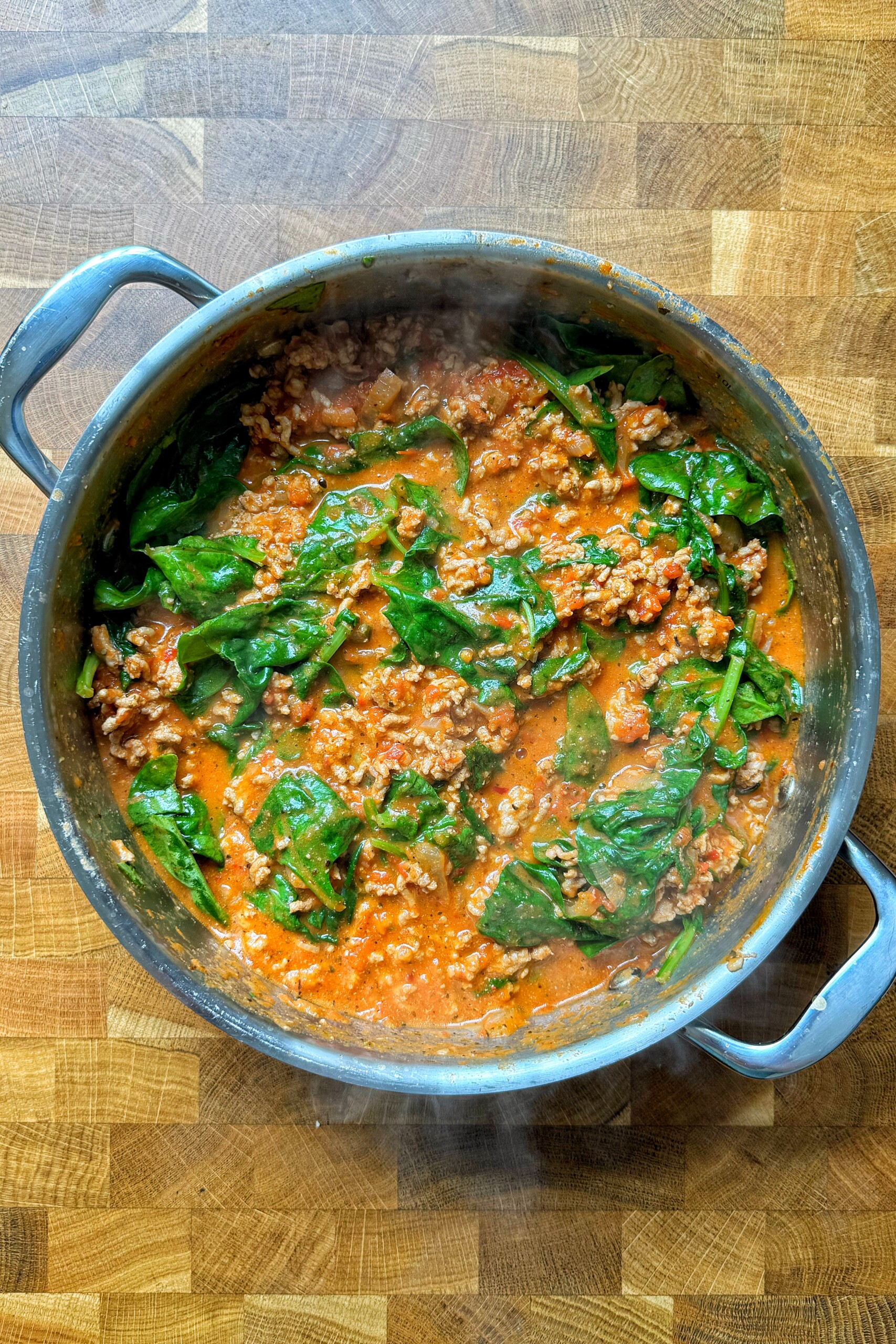 Ground turkey pasta with spinach in pan.