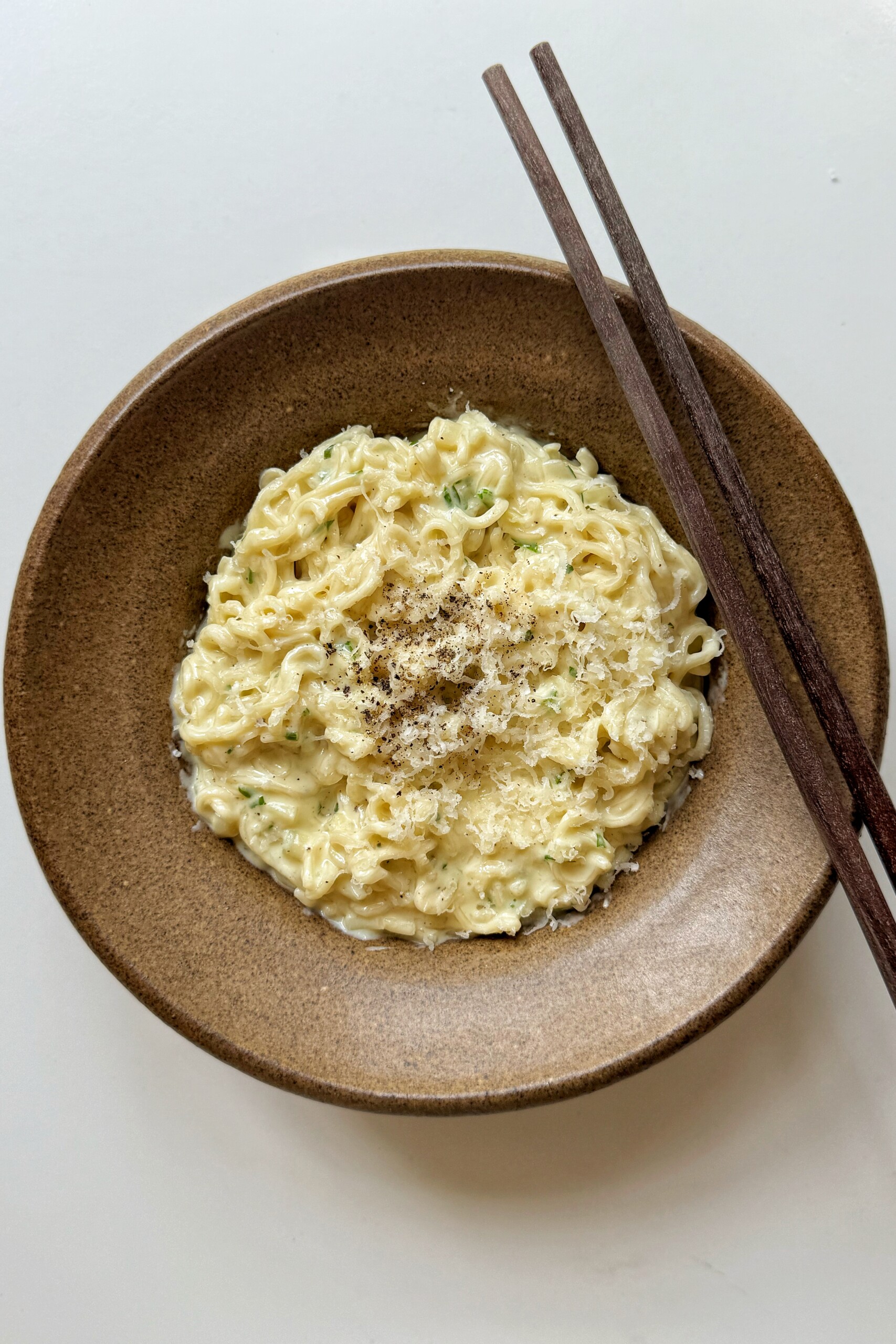 Bowl of garlic parmesan noodles with chopsticks.