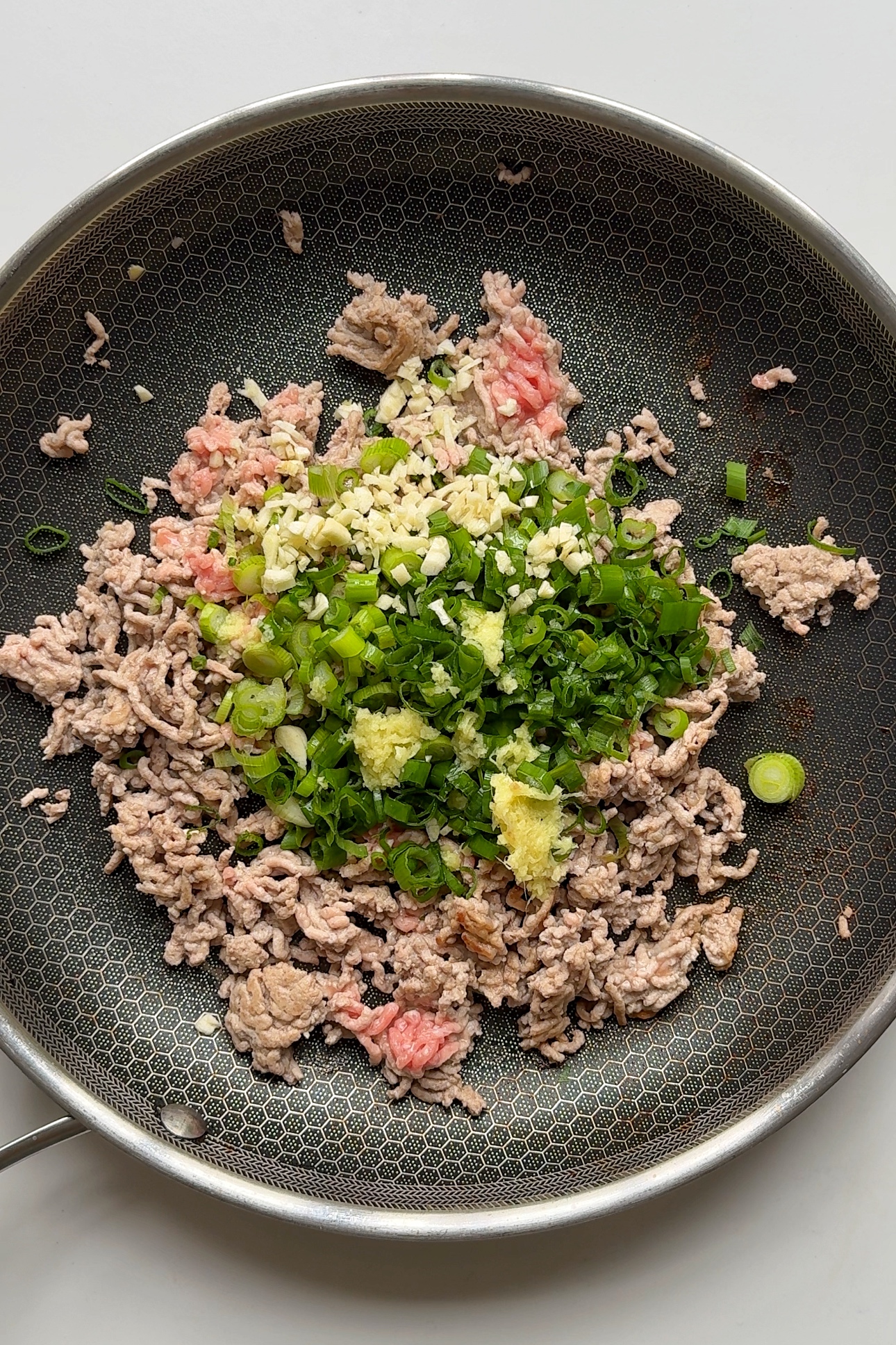 Frying ground pork with scallions and garlic in pan.