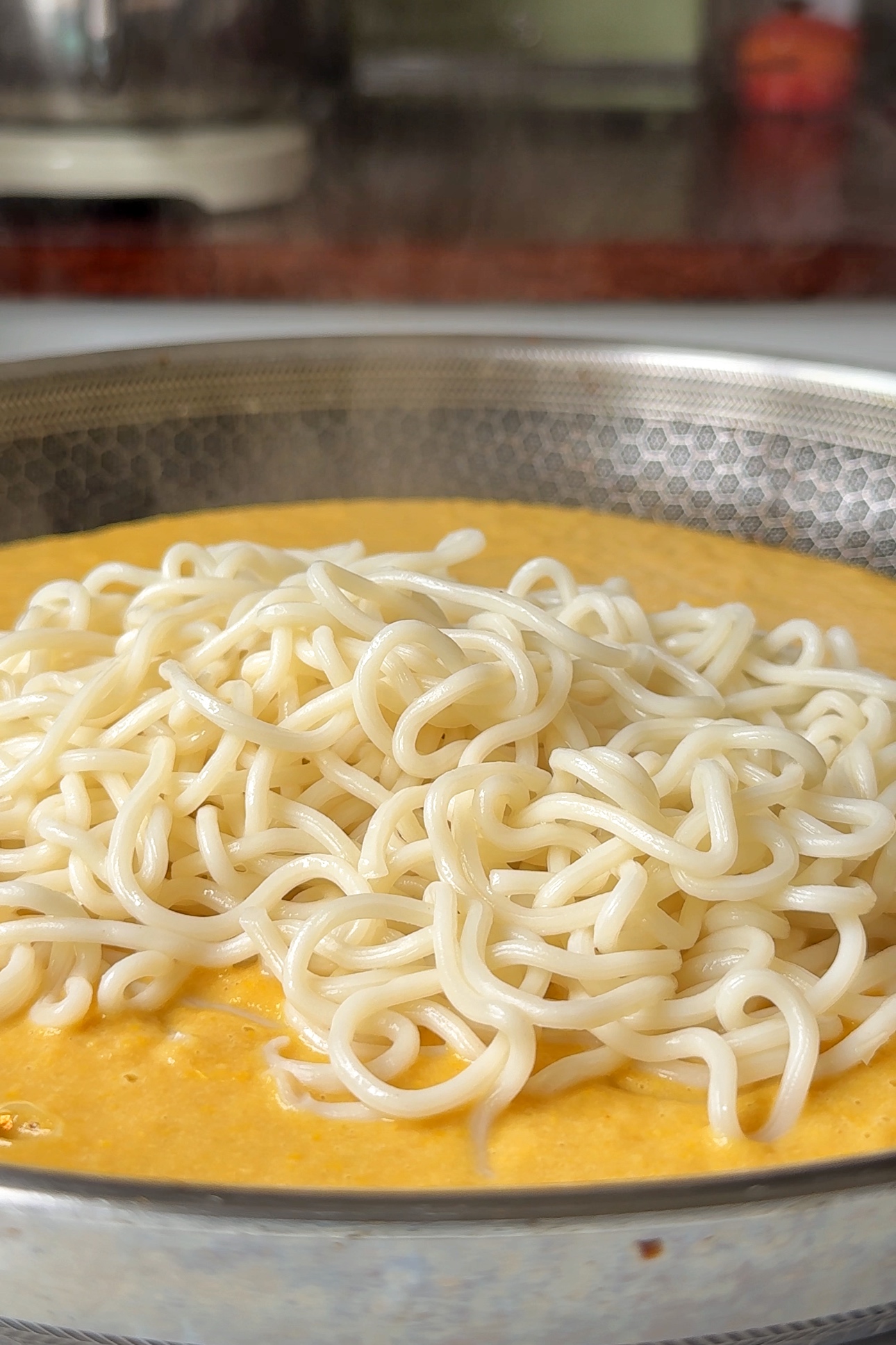 Adding noodles into sauce.