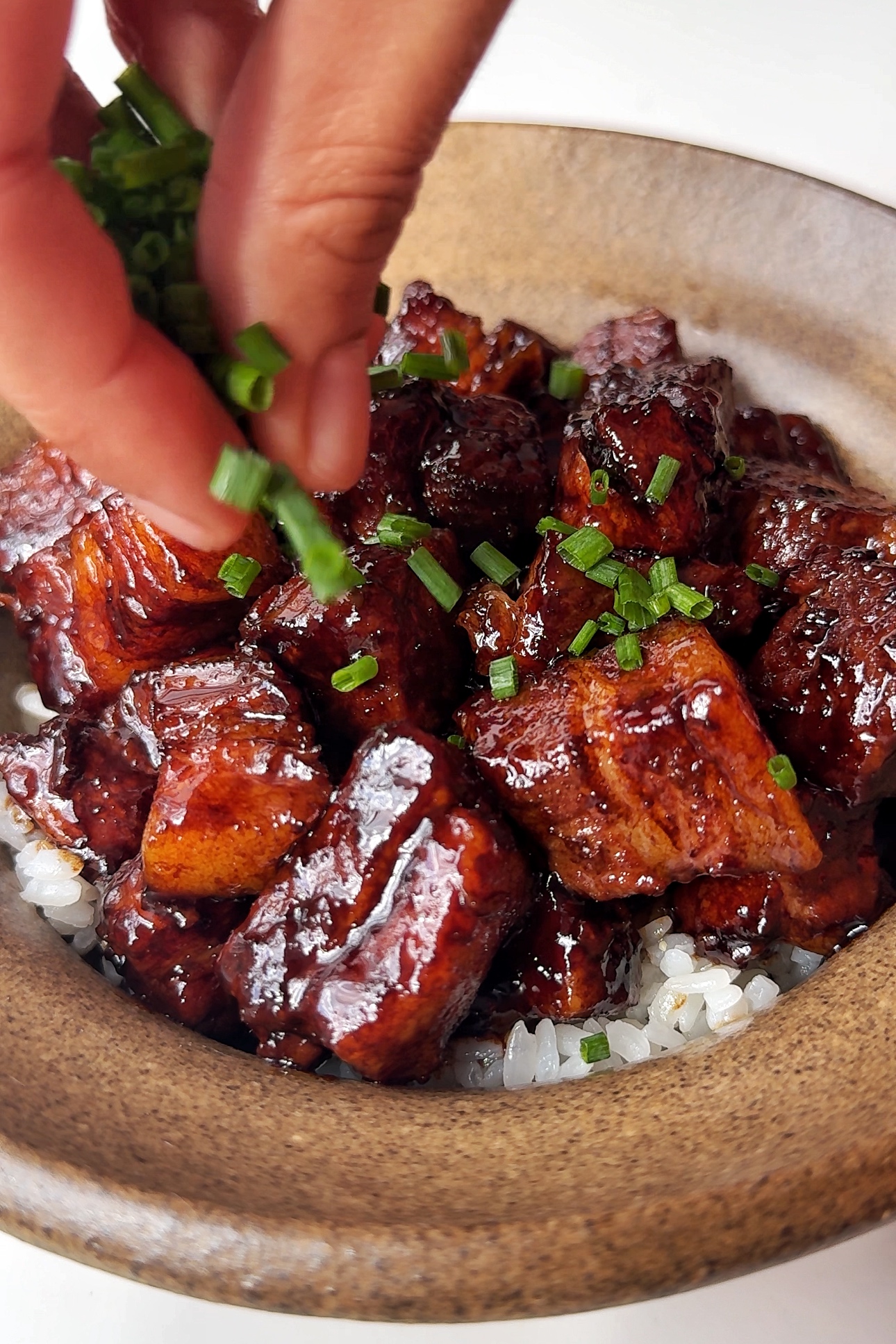 Garnishing pork belly in a bowl.