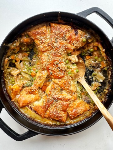 Black dish with chicken pot pie and a golden spoon.