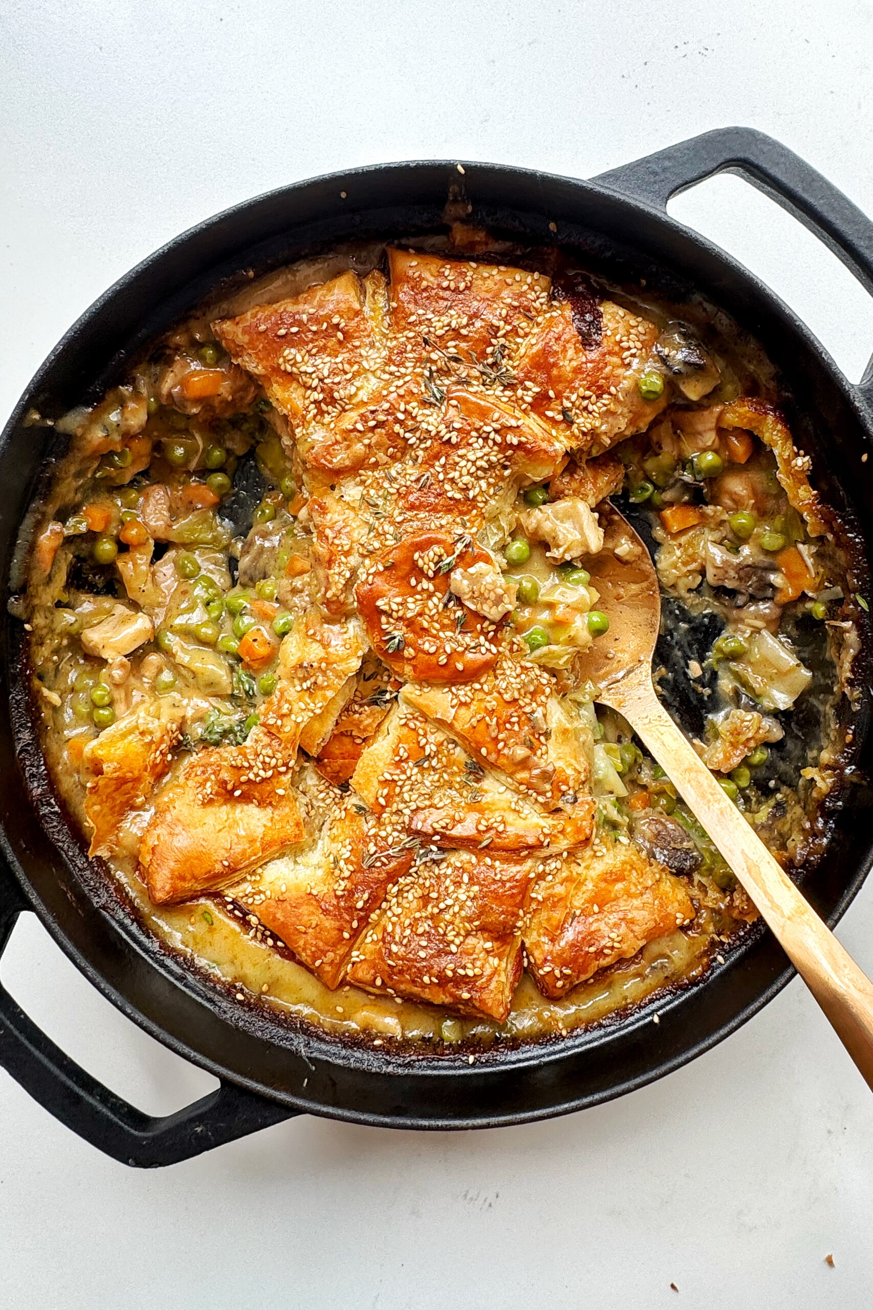 Black dish with chicken pot pie and a golden spoon.