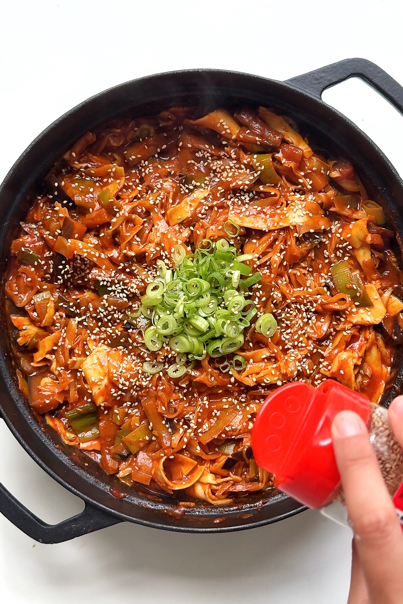 Sprinkling sesame seeds over spicy gochujang lasagne.