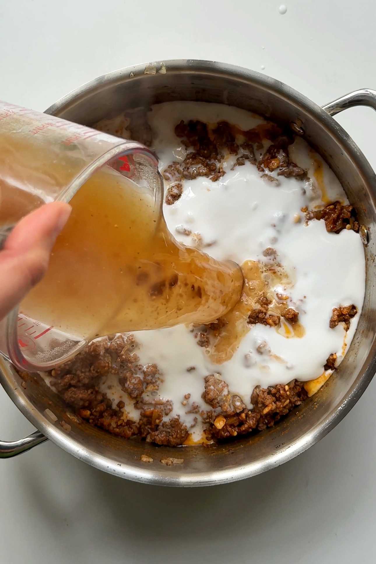 Pouring in beef stock into the pan.