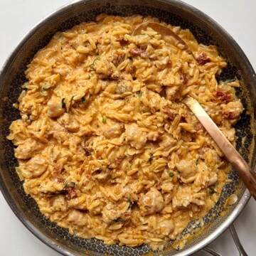 sausage orzotto in a black pan.