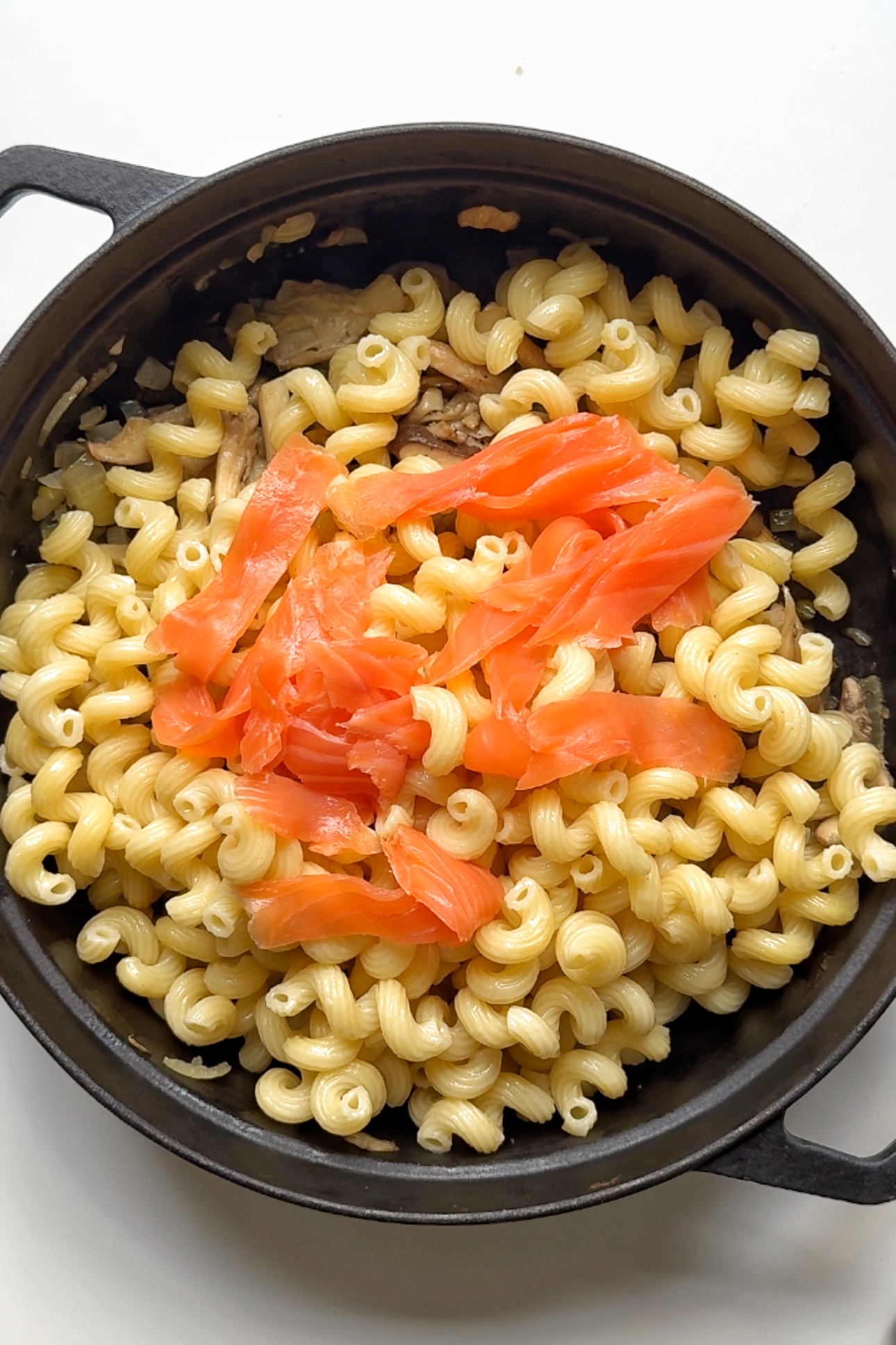 Adding pasta and smoked salmon to the pan.