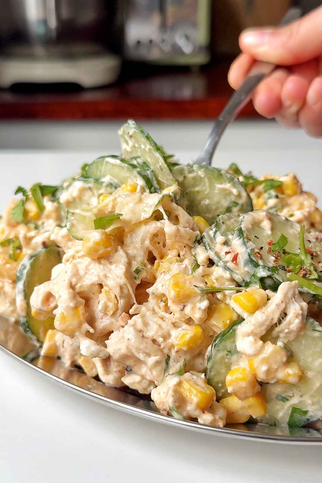 Creamy chicken cucumber salad on a metal tray on a white background.