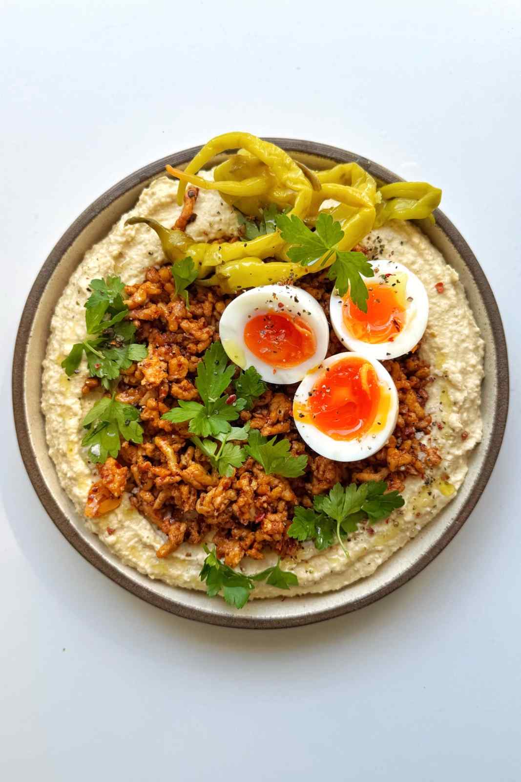 chicken hummus bowl with jammy eggs on a white background.