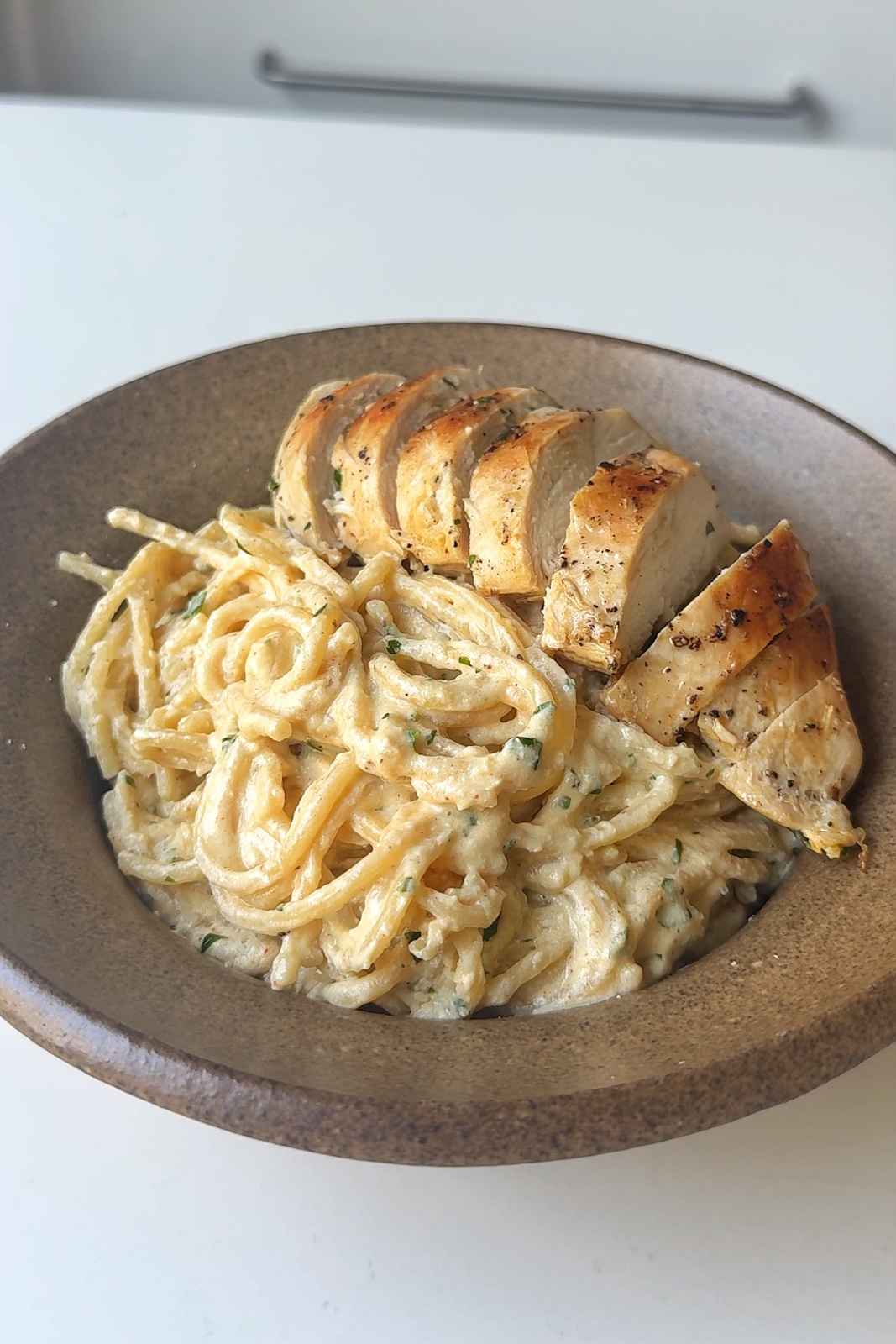 Silken tofu pasta sauce with pasta and fried chicken breast in brown bowl.