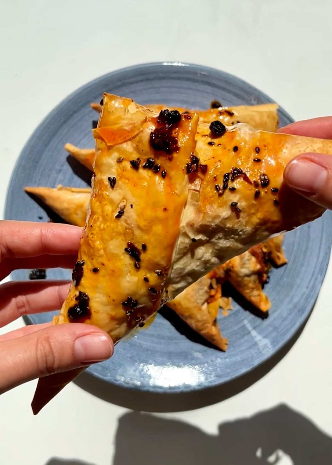 Gochujang feta pastries in golden filo triangles with spinach, feta, and gochujang filling sprinkled with sesame seeds.