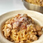 Creamy sausage pasta in a white bowl.