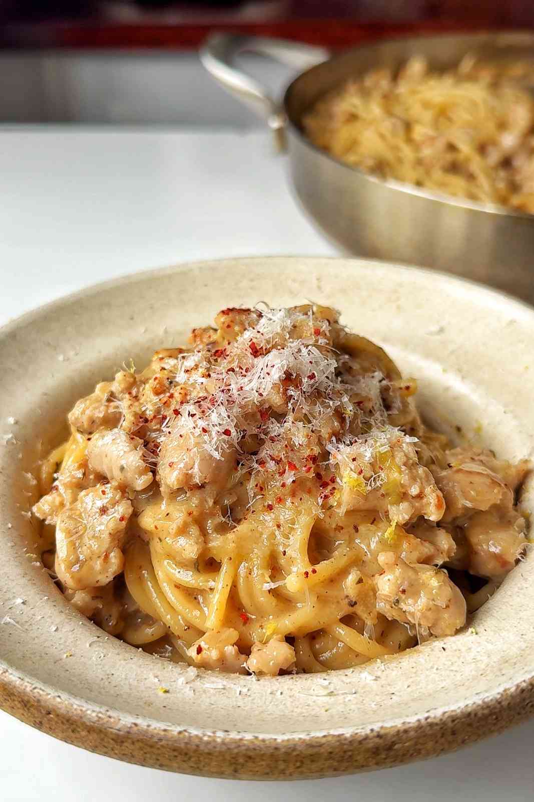 Creamy sausage pasta in a white bowl.