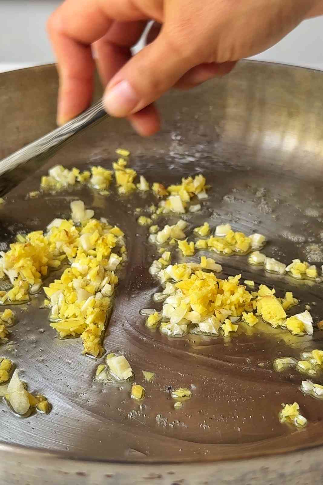 Frying garlic and ginger in a stainless steel skillet.