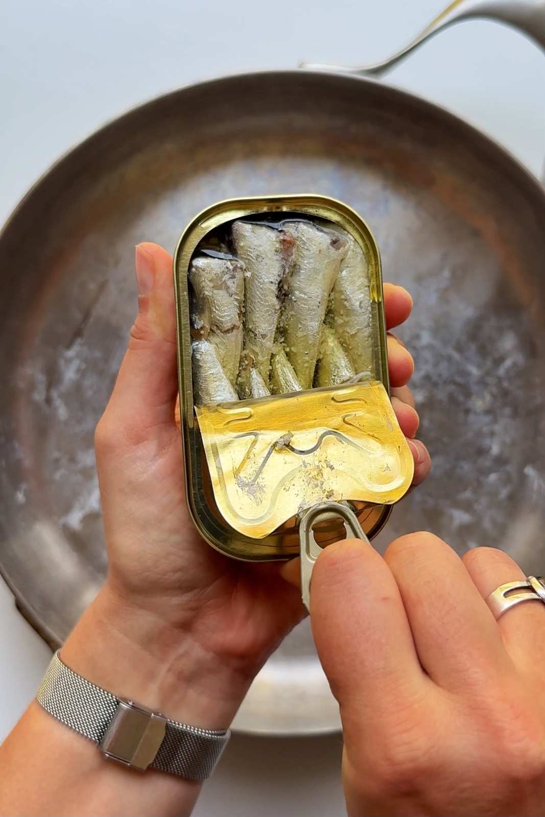 Pealing back sardine can to reveal sardines.