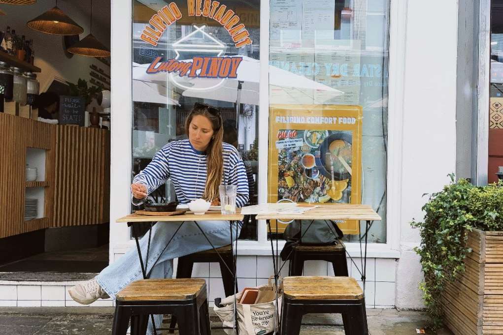 Emily Roz sitting in front of a filipino restaurant.